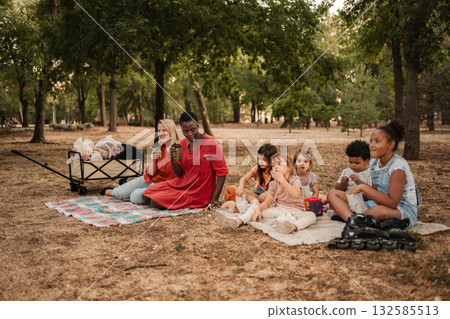 Educators and children enjoying a picnic in the park 132585513