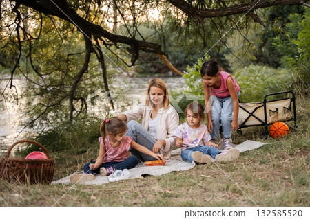 Family enjoying a summer picnic by the river Family enjoying a summer picnic by the river 132585520