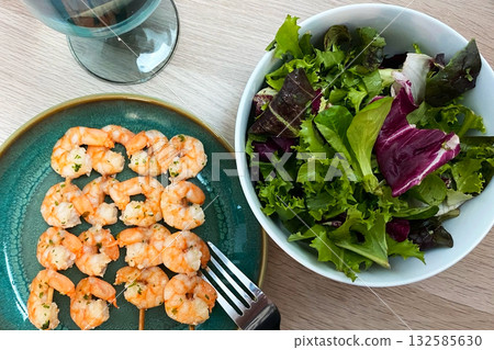 Shrimps with lettuce salad in a blue bowl on a wooden table 132585630