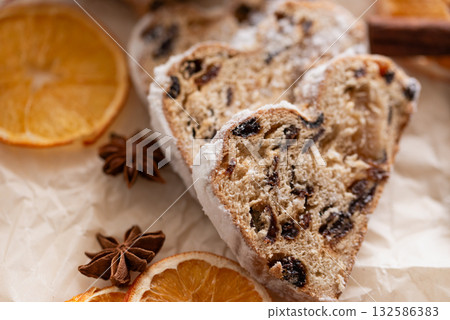 Christmas stollen on wooden background. Traditional christmas german dessert cut into pieces. Cake with nuts, raisins with marzipan and dried fruit on cutting board. baking for xmas 132586383