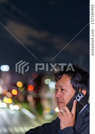 一名商人正在處理緊急情況,背景是城市的夜景;一名男員工在加班回家的路上聯繫客戶。 一名商人正在處理緊急情況,背景是城市的夜景;一名男員工在加班回家的路上聯繫客戶。 132586466