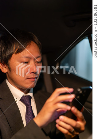 A businessman communicating with a smartphone while traveling to a client's location A businessman communicating with a smartphone while traveling to a client's location 132586581