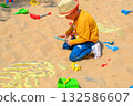 Good leisure for a child. Teaching a child through play. A handsome boy 3 oldl in a yellow jacket excavates the remains of dinosaurs. High quality photo. 132586607