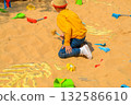 Good leisure for a child. Teaching a child through play. A handsome boy 3 oldl in a yellow jacket excavates the remains of dinosaurs. High quality photo. 132586610