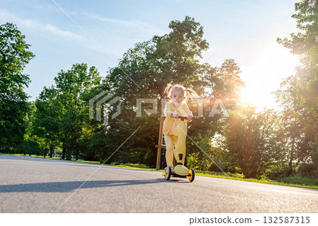 Girl on scooter. Riding child outdoor fun. Sunshine road freedom lifestyle. Girl on scooter. Riding child outdoor fun. Sunshine road freedom lifestyle. 132587315