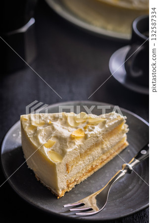 Sweet creamy cake on plate on black table. 132587334