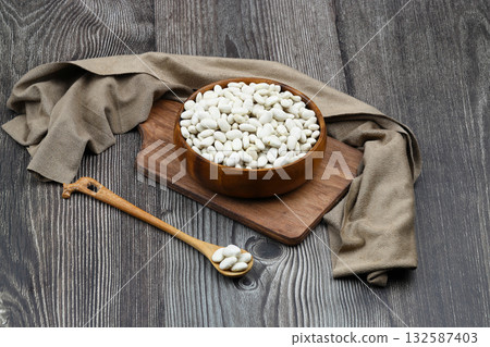 white kidney bean in wooden bowl isolated on wooden background. Top view. Flat lay white kidney bean in wooden bowl isolated on wooden background. Top view. Flat lay 132587403
