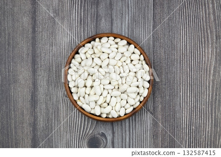 white kidney bean in wooden bowl isolated on wooden background. Top view. Flat lay white kidney bean in wooden bowl isolated on wooden background. Top view. Flat lay 132587415