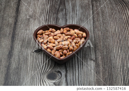 red kidney beans in wooden bowl isolated on dark background. red kidney beans in wooden bowl isolated on dark background. 132587416