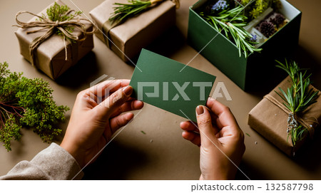 A person holding a green business card in front of a bunch of presents 132587798