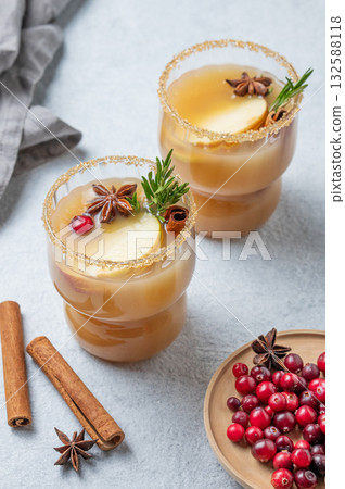 Two glasses of hot apple cider with cinnamon, anise, brown sugar and rosemary on a light background 132588118