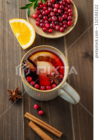 A mulled wine in a mug with cinnamon, berries and fruits on a dark wooden background. 132588122