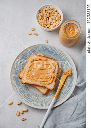 Peanut butter toast on a plate on a light background with nuts, napkin and knife. Peanut butter toast on a plate on a light background with nuts, napkin and knife. 132588195
