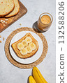 Peanut butter toast with banana on a plate on a light background with spread, bread, fruit  132588206