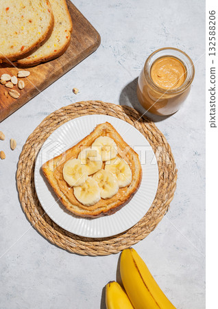 Peanut butter toast with banana on a plate on a light background with spread, bread, fruit Peanut butter toast with banana on a plate on a light background with spread, bread, fruit 132588206