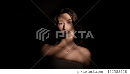 Young woman posing in the shadows with stripes of light illuminating her face Young woman posing in the shadows with stripes of light illuminating her face 132588228