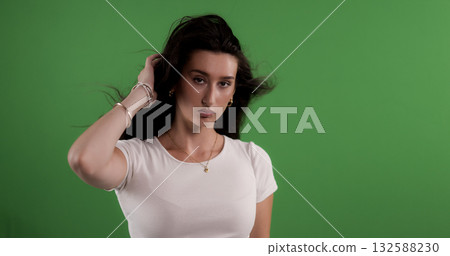 Young woman touching her hair on green screen background Young woman touching her hair on green screen background 132588230