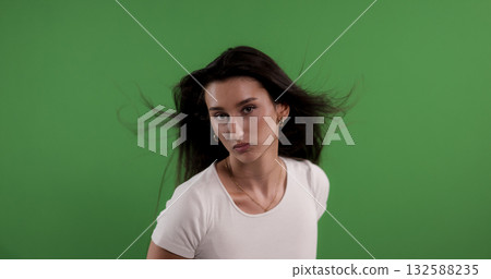 Young woman with blowing hair posing on green screen background 132588235
