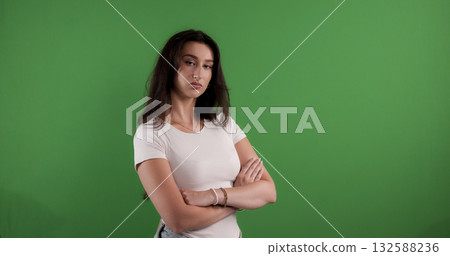 Serious young woman with crossed arms posing on green screen background Serious young woman with crossed arms posing on green screen background 132588236