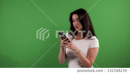 Young woman using smartphone on green screen background 132588239