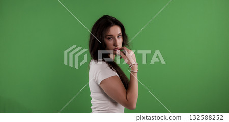 Young woman posing touching her face on green screen background Young woman posing touching her face on green screen background 132588252