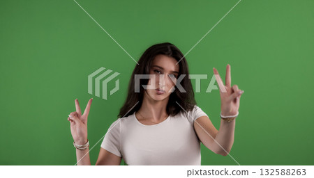 Young woman making peace sign with both hands on chroma key background 132588263