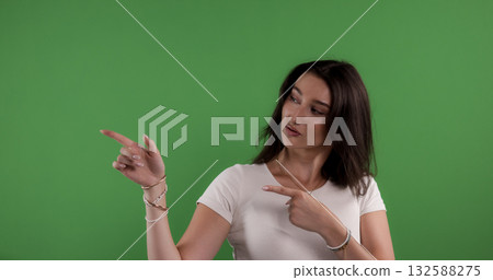 Young woman pointing with index fingers on green screen background 132588275