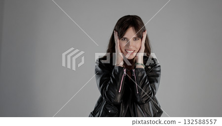 Excited young woman covering ears with hands and smiling Excited young woman covering ears with hands and smiling 132588557