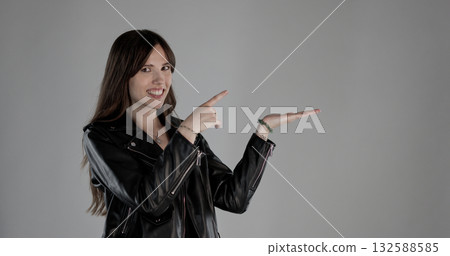 Young woman pointing and showing with hands on gray background Young woman pointing and showing with hands on gray background 132588585