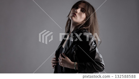 Young woman wearing black leather jacket posing in studio Young woman wearing black leather jacket posing in studio 132588588