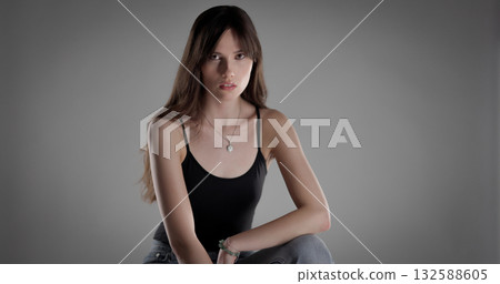 Young woman posing and looking serious with long hair and black top 132588605