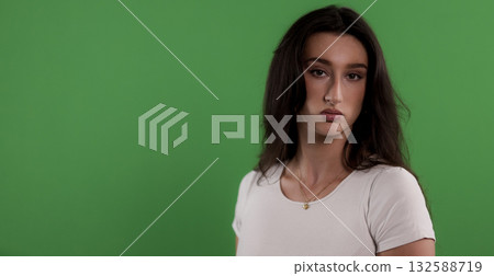 Serious young woman with long brown hair posing on green screen background Serious young woman with long brown hair posing on green screen background 132588719