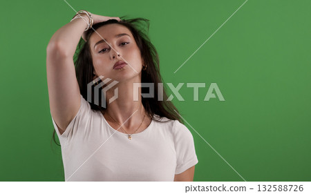 Young woman touching her hair on green screen background 132588726