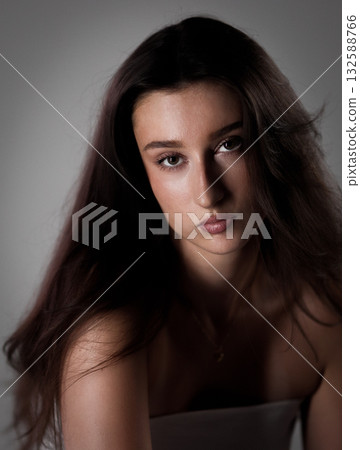 Portrait of a serious young woman with long brown hair posing in studio Portrait of a serious young woman with long brown hair posing in studio 132588766