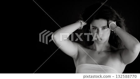 Young woman holding her hair with bracelets on black background Young woman holding her hair with bracelets on black background 132588770