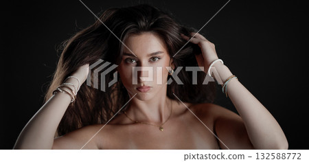 Young woman playing with her long hair on black background Young woman playing with her long hair on black background 132588772