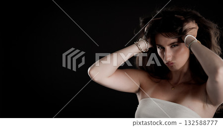 Young woman holding her hair with bracelets and necklace posing on black background Young woman holding her hair with bracelets and necklace posing on black background 132588777