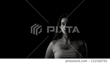 Young woman emerging from darkness with half face illuminated in black and white 132588791