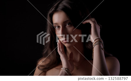 Fashion model posing with bracelets and necklace, touching her hair and face Fashion model posing with bracelets and necklace, touching her hair and face 132588797