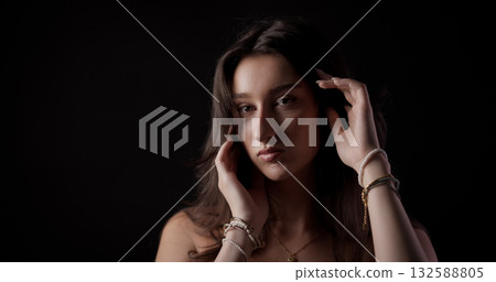 Young woman touching her hair and posing on black background 132588805