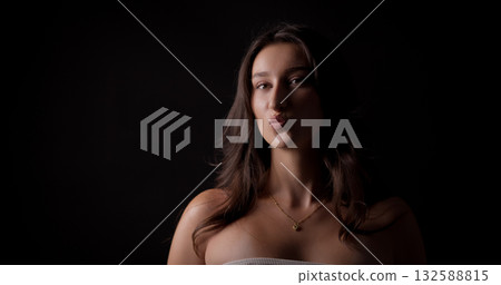 Young woman puckering lips on black background Young woman puckering lips on black background 132588815
