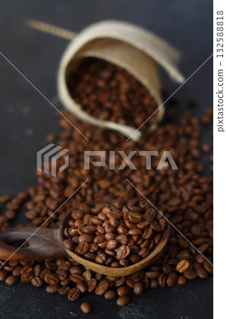Fresh roasted arabica coffee beans in a wooden spoon and scattered coffee beans on a wooden table. Fresh roasted arabica coffee beans in a wooden spoon and scattered coffee beans on a wooden table. 132588818