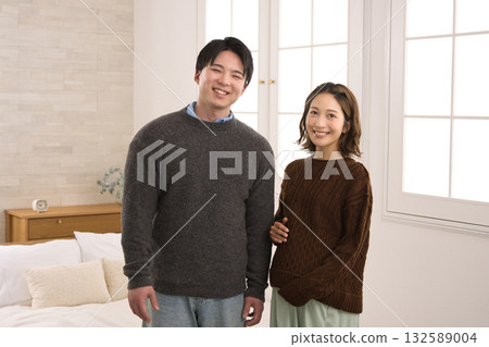 一對年輕夫婦站在窗邊,一名孕婦 一對年輕夫婦站在窗邊,一名孕婦 132589004