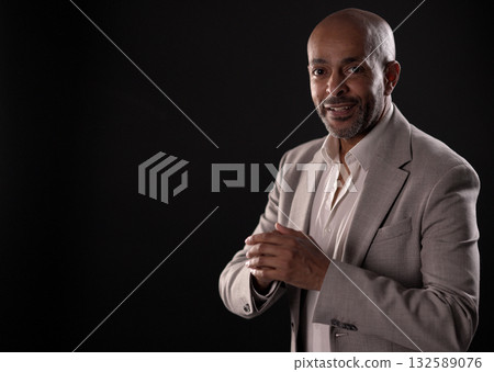 Smiling african american businessman rubbing hands on black background 132589076