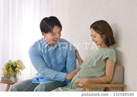 一對年輕夫婦在沙發上休息，孕婦 132589180