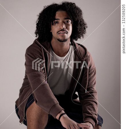 Young african american man with curly hair crouching and posing in studio Young african american man with curly hair crouching and posing in studio 132589205
