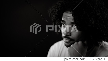 Pensive young african american man with hand on chin looking away on black background Pensive young african american man with hand on chin looking away on black background 132589231