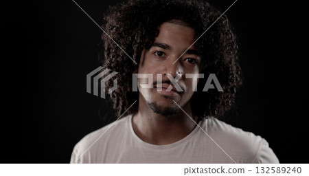 Portrait of young African American man with curly hair posing on black background Portrait of young African American man with curly hair posing on black background 132589240