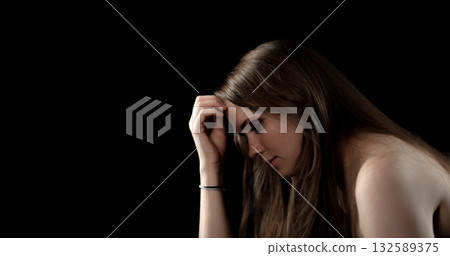 Young woman suffering from headache touching her forehead on black background 132589375