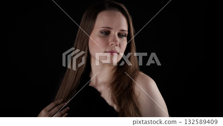 Studio portrait of a beautiful model looking away touching her hair 132589409